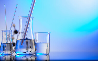 Laboratory concept background. Glass tubes and beakers on blue background.