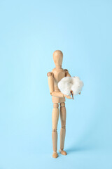 Wooden mannequin with cotton flower on color background