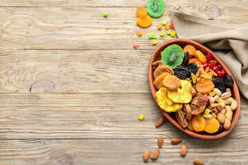 Plate with different dried fruits and nuts on wooden background