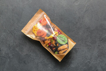 Bag with different dried fruits on dark background