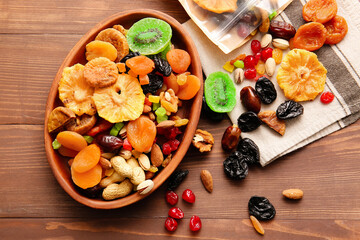Plate and bag with different dried fruits and nuts on wooden background