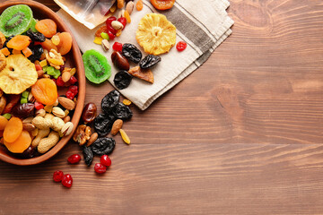 Plate and bag with different dried fruits and nuts on wooden background