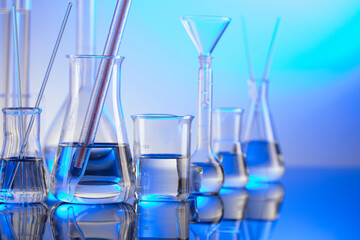 Laboratory concept background. Glass tubes and beakers on blue background.