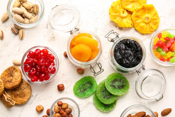 Bowls and jars with different dried fruits and nuts on light background