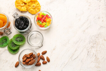 Bowls and jars with different dried fruits and nuts on light background