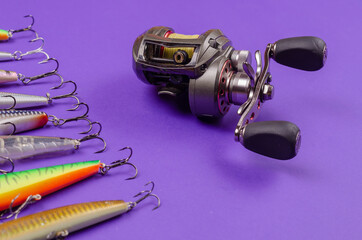 Artificial lures for fishing for predatory fish and a fishing reel on a blue background.
