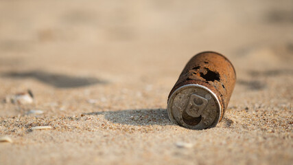 Old rusty can dropped on the sand beach.