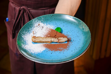 Delicious modern cocoa cake with chocolate and cream on a white plate. Served by waiter in restaurant or cafe
