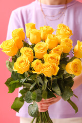 Young woman with beautiful yellow roses on color background, closeup