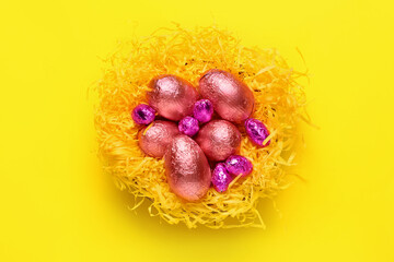 Nest with sweet chocolate eggs on color background
