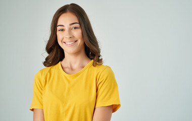 Obraz premium pretty brunette in a yellow t-shirt gray background smile emotions