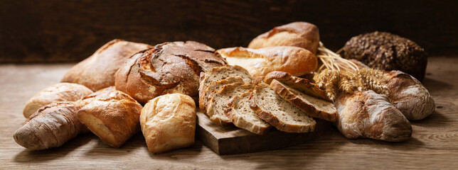 Fresh baked bread and wheat ears on a wooden table