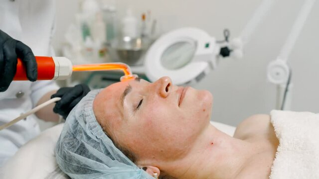Facial massage of a patient in a cosmetic spa salon using a device with a high-frequency current