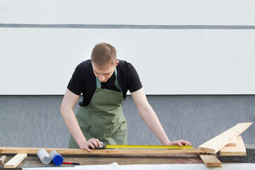. A young male designer paints a wooden Board white with a brush. 