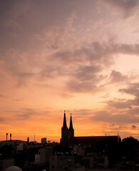 Obraz premium Beautiful red and blue sunrise sky with clouds over black silhouette of city with tower of church on horizon. Silhouette of the catholic church and cross