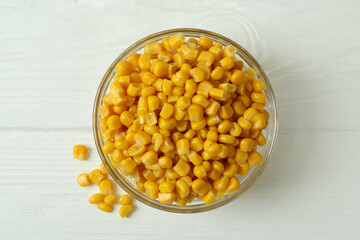 Bowl with canned corn on white wooden background