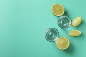 Shots and lime slices on mint background, space for text