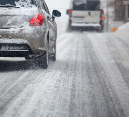Road snow pieces flow from wheels of dirty car moving fast in daylight city with selective focus.