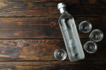 Fototapeta na wymiar Blank bottle of vodka and shots on wooden background