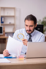 Young businessman employee holding loupe in auditing concept