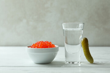 Shot of vodka, caviar and pickle on white wooden background