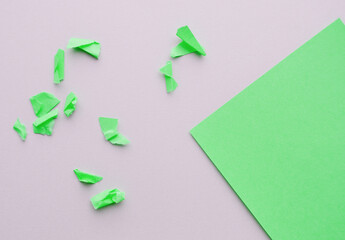 Corner green paper with a copy of the space on a gray background and small torn and crumpled pieces...