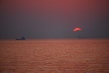 伊勢湾の鮮やかな夕焼けと海の日の入りの風景と海面の船の姿