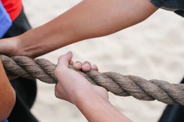 Hand pulls and holding a wide knitted rope. Children's games - tug of war