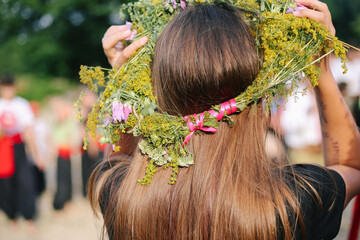 Naklejka premium Girl from the back in a wreath of flowers, wildflowers at the celebration of a traditional Slavic holiday Ivana Kupala