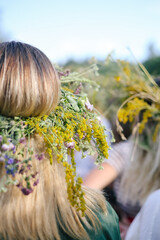 Naklejka premium Girl from the back in a wreath of flowers, wildflowers at the celebration of a traditional Slavic holiday Ivana Kupala