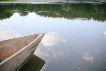 Old small wooden rowboat boat stands by the lake