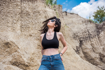 sporty girl in top and jeans posing in summer in a sandy mountain quarry