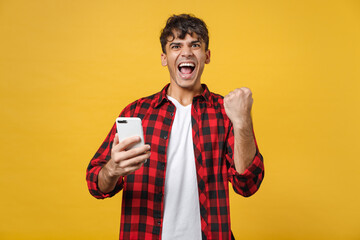 Young spanish latinos excited fashionable man 20s wearing red checkered shirt holding mobile cell...