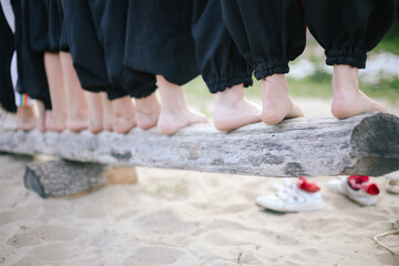 Bottom: Many dirty bare feet stand on a wooden log in black pants