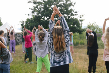 Girl pulls her hands up. Group of children doing morning exercises yoga-sport outdoors in nature in a summer camp