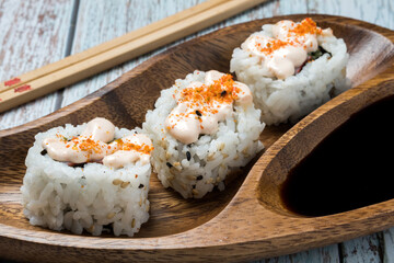Detail view of three pieces of uramaki sushi with soja