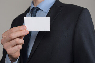 Businessman ,Business Man's hand hold showing business card - close up shot on grey background. Show a blank piece of paper. Paper visit card