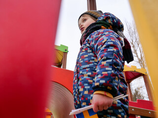 Fototapeta na wymiar Little kid play alone on playground in winter.