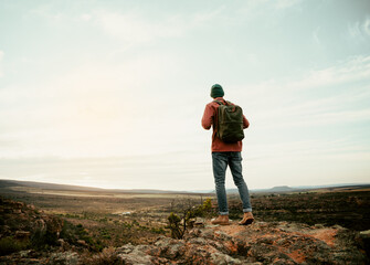 Caucasian adventurer male hiking on mountain with backpack looking over horizon 