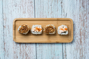 Four pieces of uramaki sushi on a wood plate