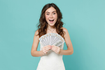Surprised bride young woman 20s in beautiful white wedding dress hold fan of cash money in dollar...