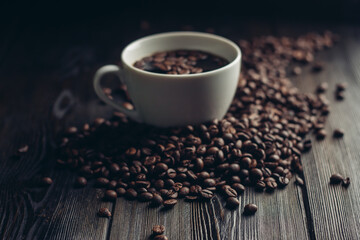 coffee beans scattered on a wooden table and a cup with a hot drink aroma