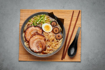 A Shoyu Ramen in gray bowl on concrete table top. Japanese cuisine meat noodle soup with chashu...