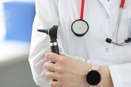 Otorhinolaryngologist holding otoscope in his hands in clinic closeup