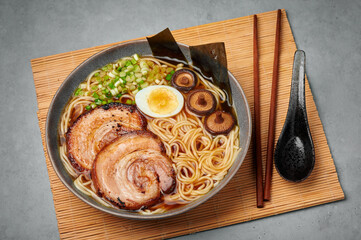 A Shoyu Ramen in gray bowl on concrete table top. Japanese cuisine meat noodle soup with chashu...