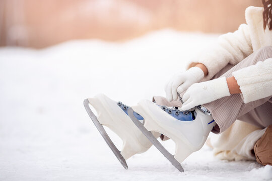 Banner woman tying shoelaces on ice skates before skating on rink - Powered by Adobe