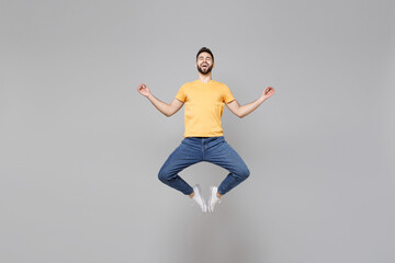 Full length of young bearded man 20s wearing yellow basic t-shirt jump high hold hands in yoga...