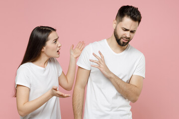 Young irritated dissatisfied couple two friends man woman in white basic t-shirt quarrel swearing have problem stress need family psychologist isolated on pastel pink color background studio portrait