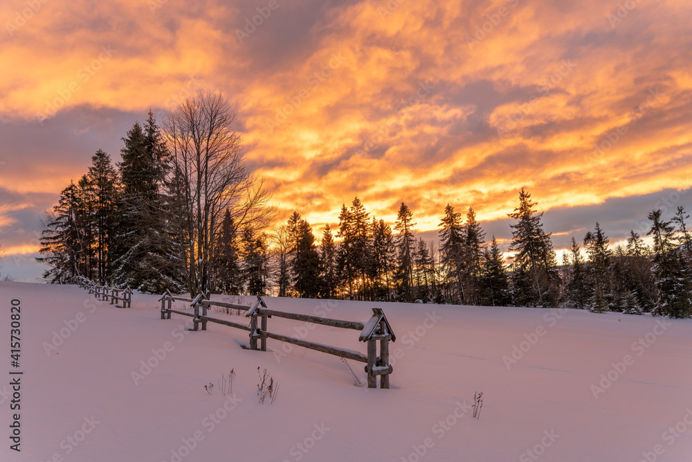 Wall mural a fiery, dramatic sunrise in a winter mountain scenery
