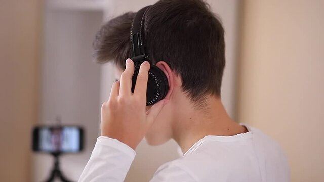 Process of teenage boy puts on headphones befour starting play games. Side view of boy preparing for gaming. Close up
